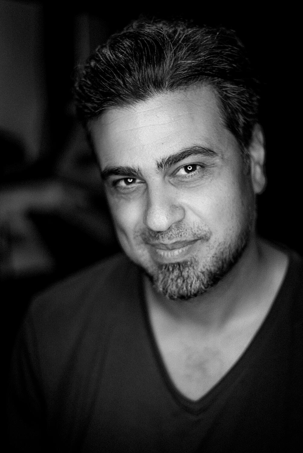 Portrait of Arash Afshar, creative director and photographer, in a high-contrast black-and-white headshot.